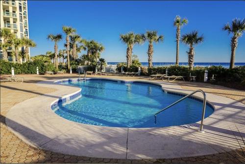 a large swimming pool with palm trees and the ocean at Destin Towers 1E in Panama City