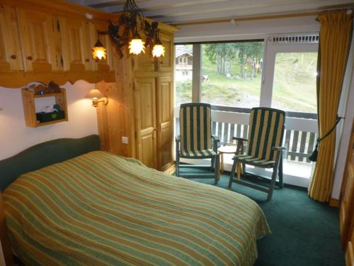 ein Schlafzimmer mit zwei Stühlen und einem Bett und einem Balkon in der Unterkunft Appartement skis aux pieds avec vue piste, 6 pers - FR-1-514-8 in Courchevel