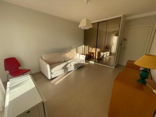 un salon avec un canapé blanc et une chaise rouge dans l'établissement Lovely Sunny Studio, à Menton