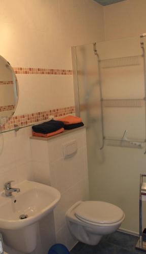 a white bathroom with a toilet and a sink at Villa Mignon - Apartment Rot in Koserow