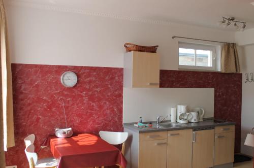 a kitchen with a red wall and a table at Villa Mignon - Apartment Rot in Ostseebad Koserow