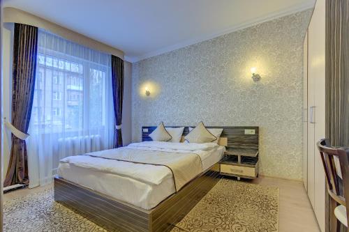 a bedroom with a large bed and a large window at Resident Hotel Almaty in Almaty