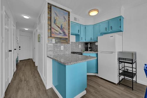 a kitchen with blue cabinets and a white refrigerator at Bleu Oasis in Galveston