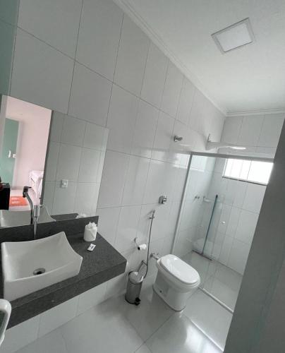 a white bathroom with a toilet and a sink at Pousada Flores do Jalapão in São Félix do Tocantins