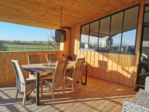a dining room with a table and chairs on a deck at le Gïte du Clocher in Saint-Julien-dʼEymet