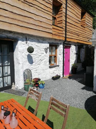 a house with a pink door and a table and chairs at Claires Cottage in Bethesda