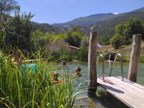Quelques personnes nageant dans une rivière dans l'établissement Gîte du bout du monde La Fenière, à Barrême
