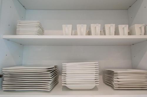 a shelf with white plates and bowls on it at Comfort exceed in this 3 BR premium in Houston! in Houston