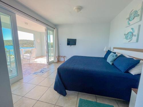 a bedroom with a blue bed and a balcony at Island Charm Culebra - Studios & Suites - Amazing Water views in Culebra Puerto Rico! in Culebra