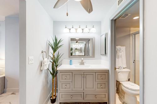 Un baño con lavabo, inodoro y espejo. en Waves & Palms Oasis, en Marco Island