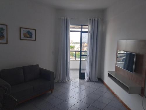 a living room with a couch and a television at flat no centro da Cidade in Campos dos Goytacazes
