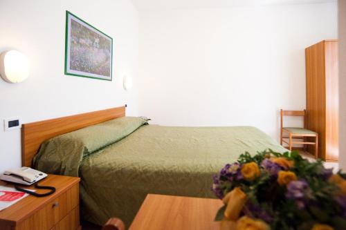 a hotel room with a bed and a table with flowers at Hotel La Toscana in Arezzo