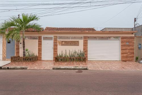 a house with two garage doors and a palm tree at Pousada Muiraquitã Parintins in Parintins
