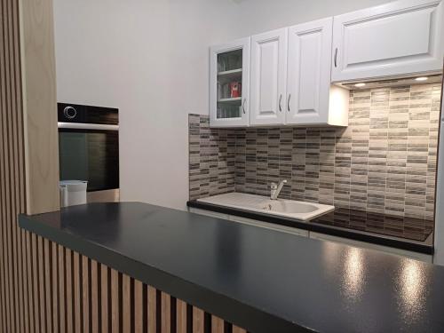 - une cuisine avec un plan de travail noir et un évier dans l'établissement La maison du soleil, à Pouzauges