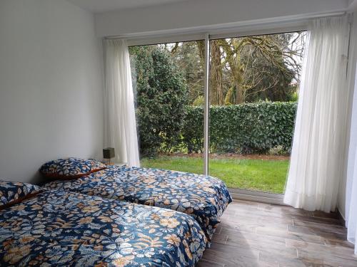 a bedroom with two beds and a large window at La maison du soleil in Pouzauges