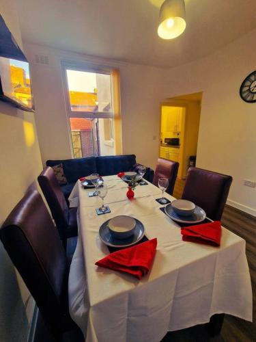 a dining room table with a white table cloth and red napkins at Beautiful home near LFC Stadium in Liverpool