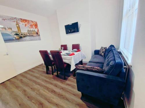 a living room with a table and a blue couch at Beautiful home near LFC Stadium in Liverpool
