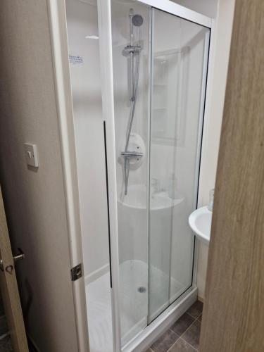 a glass shower in a bathroom with a sink at Highfield Grange Holiday Park in Little Clacton