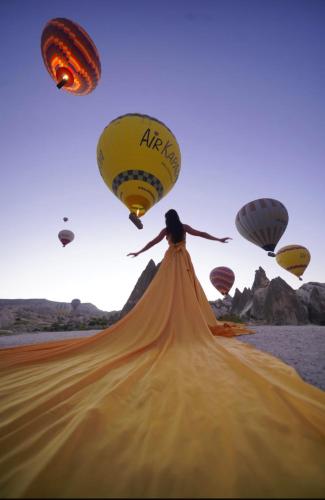 a woman is jumping in the air with hot air balloons at Asteria Cave Hotel in Goreme