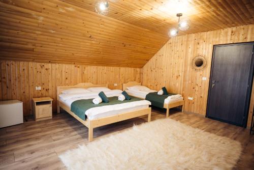 ein Schlafzimmer mit zwei Betten in einer Holzhütte in der Unterkunft Buenos Aires in Şimon