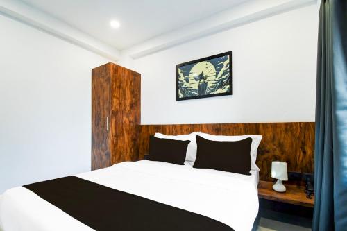 a bedroom with a white bed with a wooden headboard at Hotel O Sayhallo Citadel in Bhubaneshwar