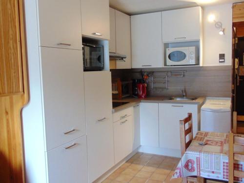 une petite cuisine avec des armoires blanches et un micro-ondes dans l'établissement Studio cosy 2 pers. avec balcon, centre Chamonix, proche commerces et pistes sk - FR-1-517-23, à Chamonix-Mont-Blanc