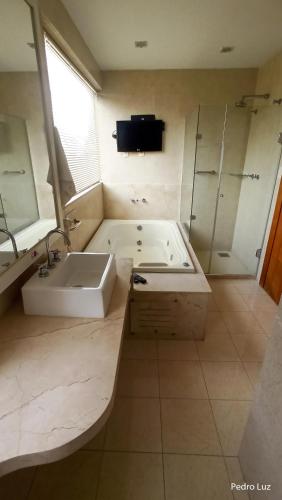 a bathroom with a tub and a sink and a shower at River Park Hotel in Resende