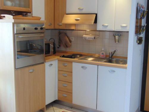 une petite cuisine avec des armoires blanches et un évier dans l'établissement Charmant 2 pièces au centre avec terrasse et garage à Chamonix - FR-1-517-41, à Chamonix-Mont-Blanc