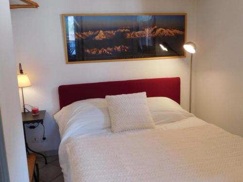 - une chambre dotée d'un lit blanc avec une photo sur le mur dans l'établissement Charmant 2 pièces au centre avec terrasse et garage à Chamonix - FR-1-517-41, à Chamonix-Mont-Blanc