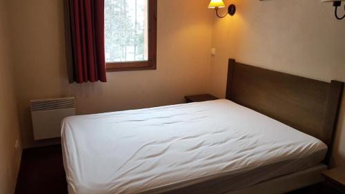 - un lit blanc dans une chambre avec fenêtre dans l'établissement Résidence L'Albane - maeva Home - Appartement 2 pièces 4 personnes - Confort MAE-2791, à Vars