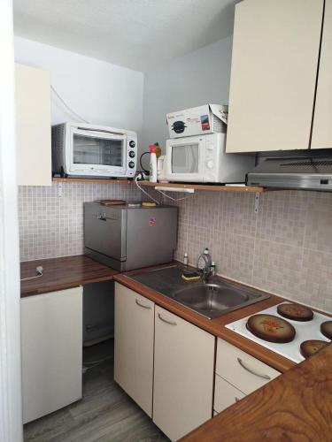 La cuisine est équipée de placards blancs, d'un évier et d'un four micro-ondes. dans l'établissement Résidence Le Tourmalet - maeva Home - Appartement 2 pièces 6 personnes - Confort MAE-5141, à La Mongie