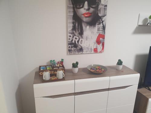 a white dresser in a room with a poster at Life Modern, Smart Appartment Balkon in Plettenberg