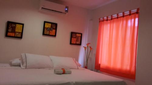 a bedroom with a white bed with a red curtain at Manzanillo Beach in Cartagena de Indias