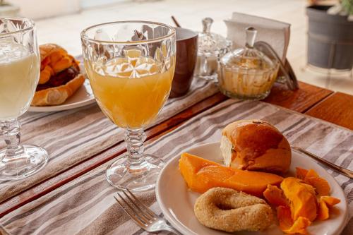 a table with plates of food and glasses of orange juice at Pousada Muiraquitã Parintins in Parintins