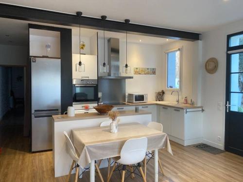 - une cuisine avec une table, une table et des chaises dans l'établissement La Maison du Clocher, à Rivedoux-Plage