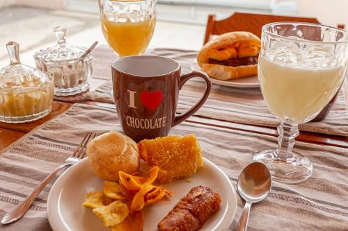 a table with a plate of food and a cup of milk at Pousada Muiraquitã Parintins in Parintins