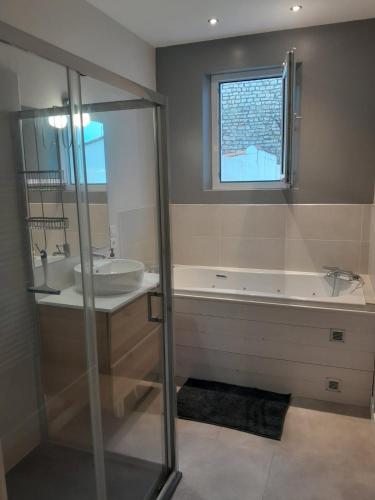 une salle de bain avec une baignoire, un lavabo et une fenêtre dans l'établissement La Maison du Clocher, à Rivedoux-Plage