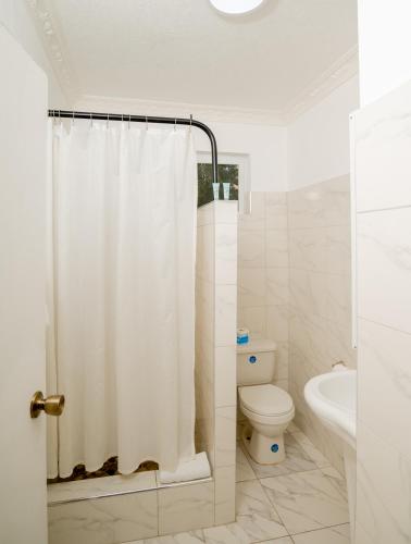 a bathroom with a shower curtain and a toilet at Beyond Sunset Resort & Villas in Treasure Beach