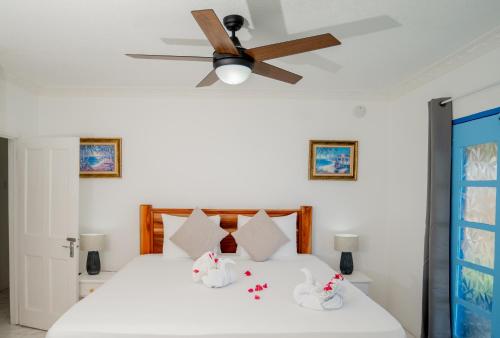 a bedroom with a white bed with a ceiling fan at Beyond Sunset Resort & Villas in Treasure Beach