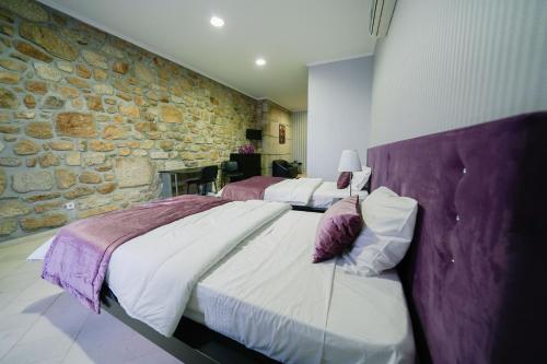 a bedroom with two beds and a stone wall at Alojamento Galerias Nascentes in Alijó