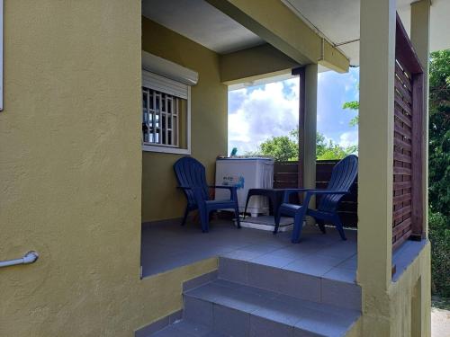 a porch with two blue chairs and a table at Claricia's 1 bedroom ,1 bathroom furnished Apt in Friar's Bay
