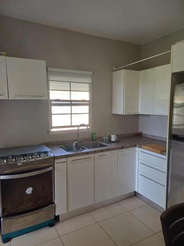 a kitchen with white cabinets and a sink and a stove at Claricia's 1 bedroom ,1 bathroom furnished Apt in Friar's Bay