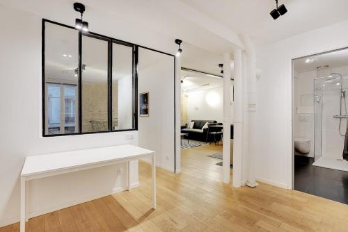 Cette chambre blanche dispose d'une table et d'un miroir. dans l'établissement LE MARAIS - UPPER CLASS Suites, à Paris