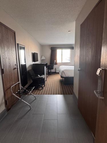 a hotel room with a bedroom and a bed and a television at Baymont Inn & Suites Richmond in Richmond