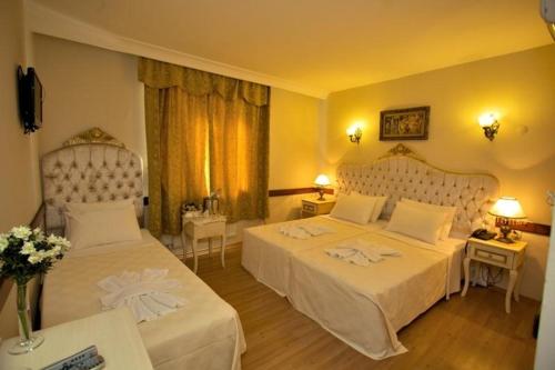 a hotel room with two beds and two tables at Adora Hotel in Istanbul