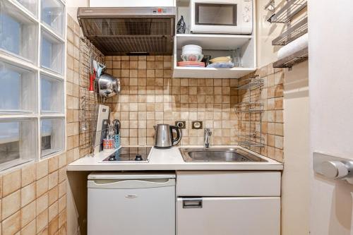 une petite cuisine avec des armoires blanches et un évier dans l'établissement Heart of Paris III, Le Marais - Charming Apartment, à Paris
