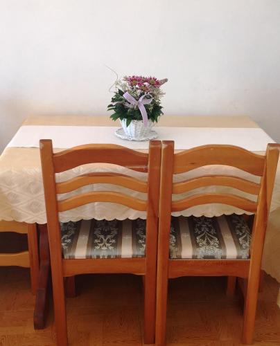 a table with two chairs and a vase of flowers on it at Bisha Apartments in Ulcinj
