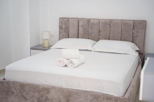 una camera da letto con un grande letto bianco con due asciugamani di Nedo Apartament's a Sarandë