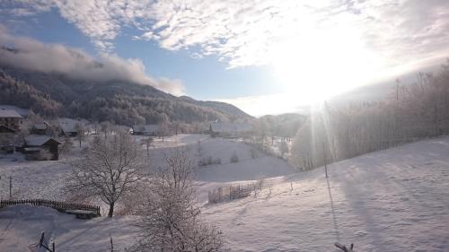 a snow covered hill with the sun in the sky at Apartment Vrtacnik in Štefanja Gora