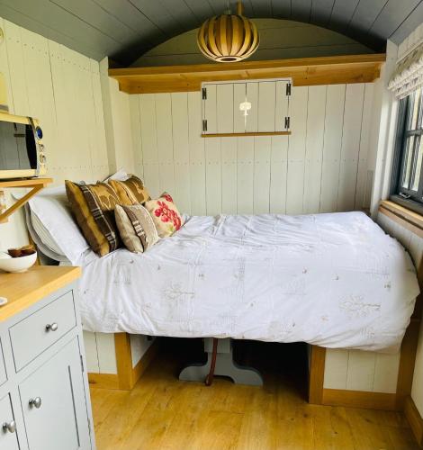 a small bedroom with a bed in the corner at Luxury shepherd hut on rare breed smallholding in Bulford
